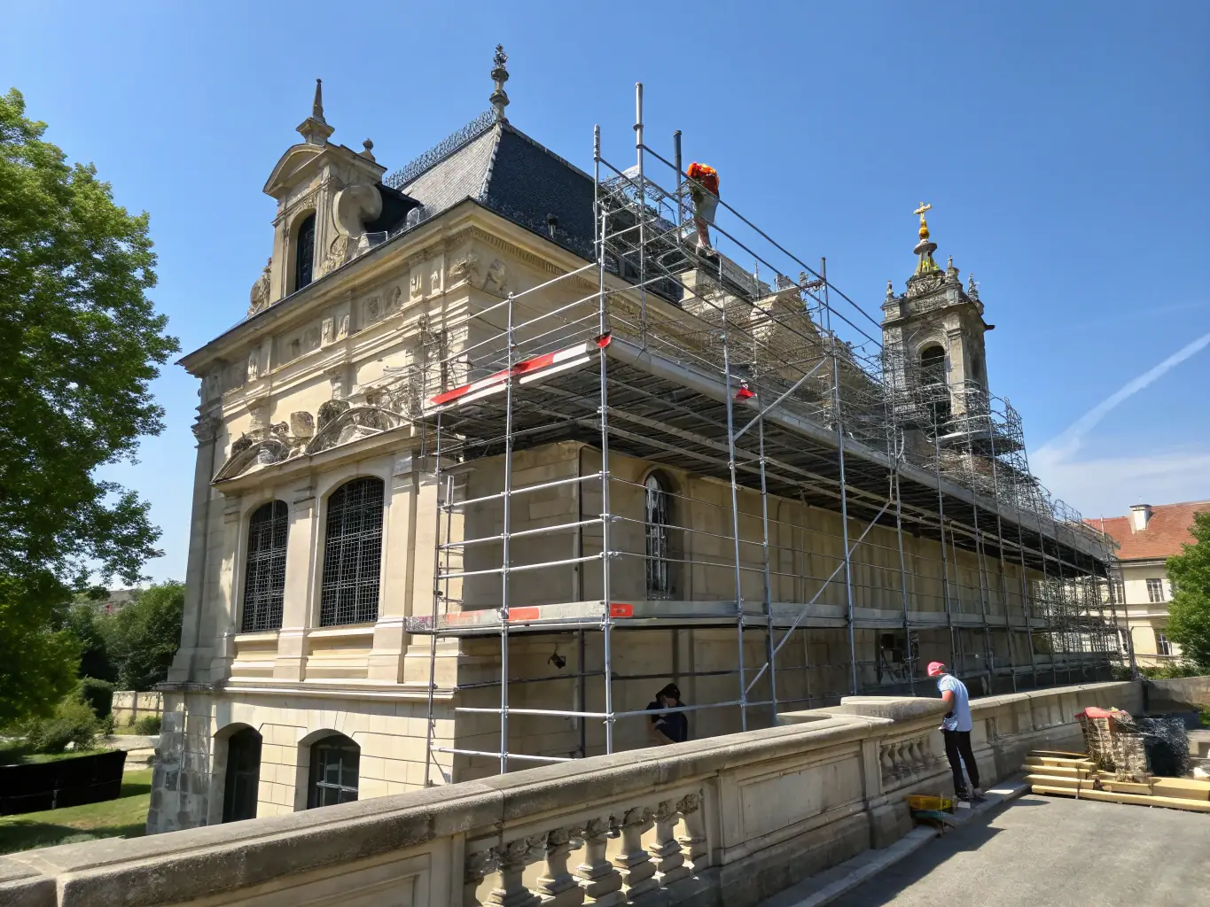 Ultra-realistic image of a skilled construction team restoring the ornate facade of a historic building, scaffolding in place, with clean white and gray tones and gold accents, conveying expertise and precision.